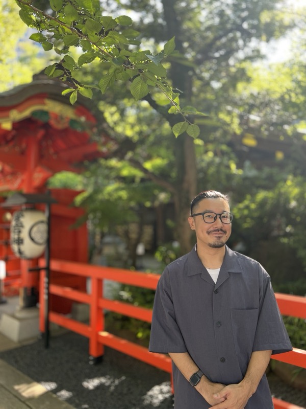 緑の木々の下に立つubweb代表 二神暢彦